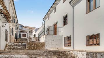 Una calle estrecha con edificios blancos, una escalera y barandillas de metal.