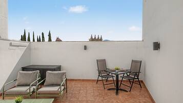 Una terraza en la azotea con una mesa, sillas y un sofá.