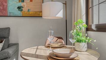 Een ronde houten tafel met een wijnglas, een schaal en een decoratieve plant in een keramieken pot.