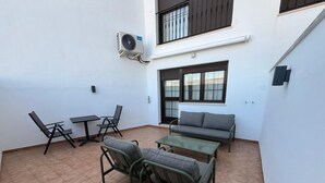 Un patio con tavolo, sedie, divano e condizionatore.