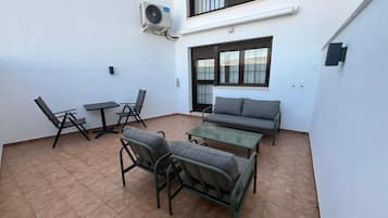 Eine Terrasse mit Tisch, Stühlen, einer Couch und einer Klimaanlage.