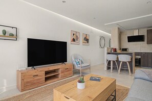 Un saló modern amb televisió de pantalla plana, moble de roba de fusta i taula de centre amb una planta.