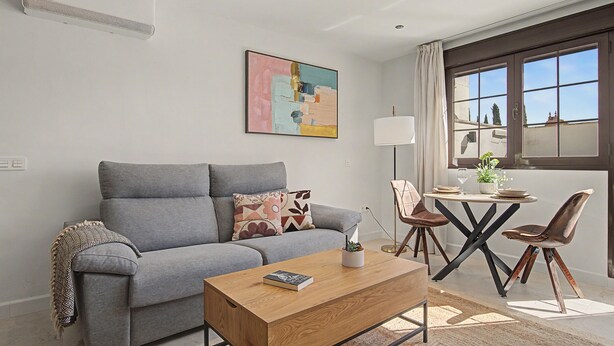 A modern living room with a grey sofa, a wooden coffee table, and a painting on the wall.