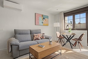 A modern living room with a grey sofa, a wooden coffee table, and a painting on the wall. - Apartment 'La Mina' with Terrace, Wi-Fi and Air Conditioning (Ronda)