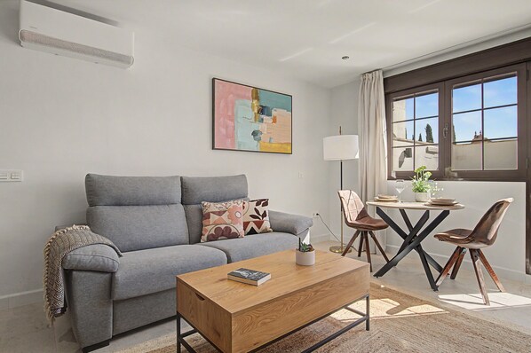 A modern living room with a grey sofa, a wooden coffee table, and a painting on the wall.