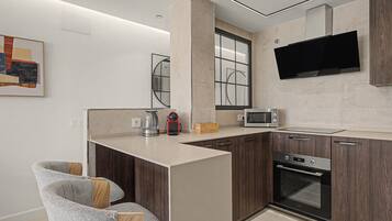 A modern kitchen with a built-in oven, microwave, and a large flat-screen TV mounted above the counter.