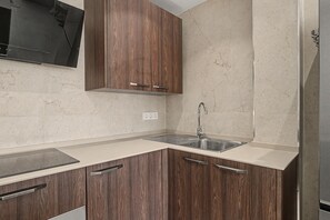 Cuina amb armaris de fusta, un rentamiques d'acer inoxidable i una superfície de treball.