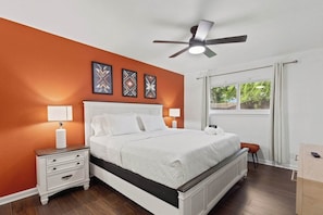 A bedroom with a bed, nightstands, a ceiling fan, and artwork on the wall.