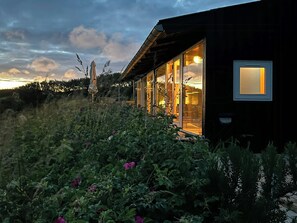 Una casa moderna con ampie vetrate, un patio in legno e vista sul cielo.