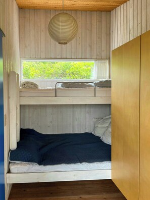 Habitación con literas, ventana, paredes de madera y lámpara colgante.