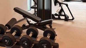 Ett gym med utrustning för styrketräning, en bänk och en konditionsträningsmaskin.