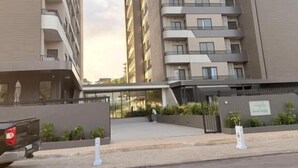 En flervåningsbyggnad med bostäder, balkonger, en grind vid entrén och en parkeringsplats.