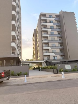 A multi-story residential building with balconies, a gated entrance, and a parking area. - loxwoodhouse (Accra)
