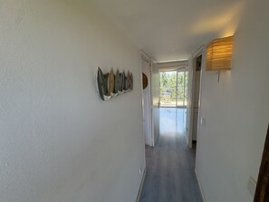 Ein Flur mit einer Reihe von Surfbrettern an der Wand, der zu einer Tür mit Blick auf einen Balkon führt.