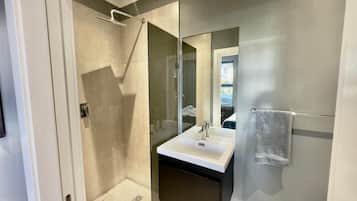 Een aparte badkuip en douche, pantoffels, handdoeken, zeep
