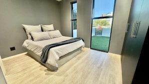 Une chambre à coucher avec un lit, une armoire et une grande fenêtre.