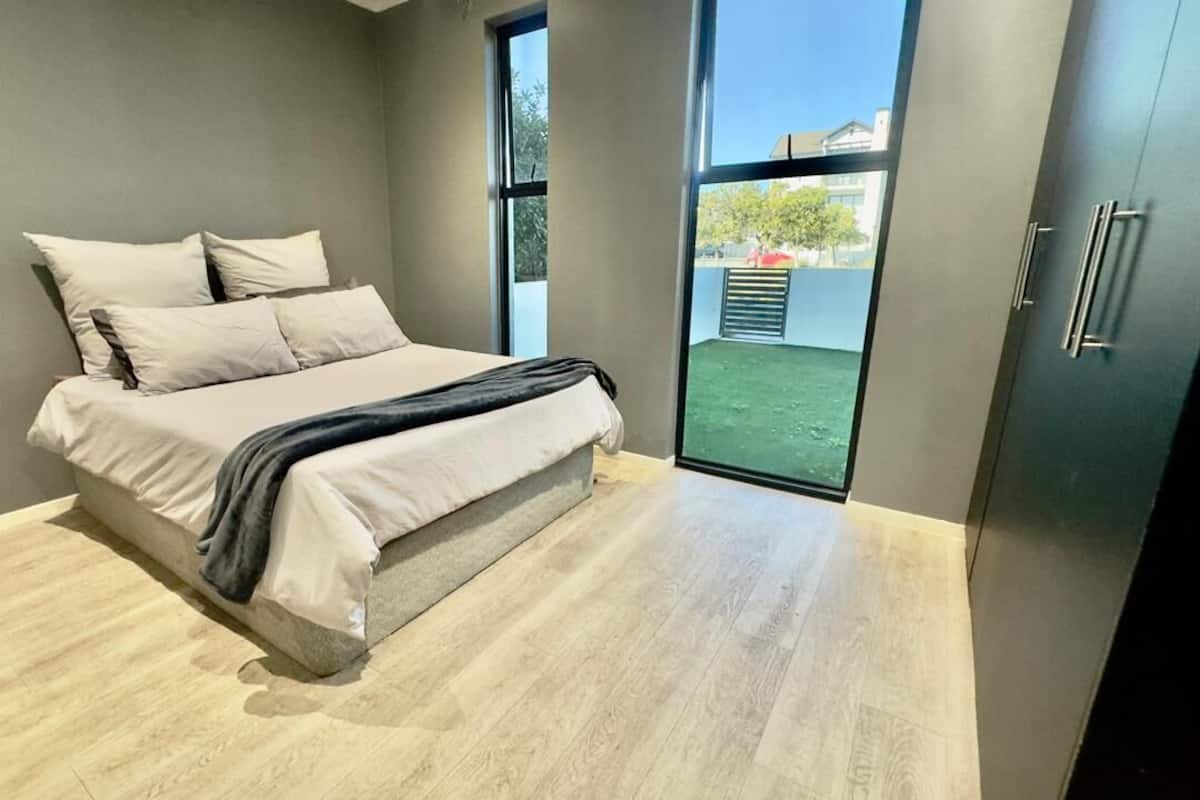 Ein Schlafzimmer mit Bett, Kleiderschrank und einem großen Fenster.