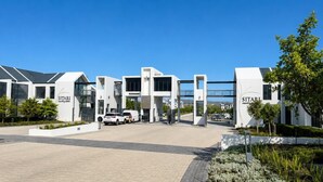 Un bâtiment moderne avec une enseigne « SITARI », une entrée pavée et un espace de stationnement.