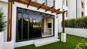 Une maison moderne dotée d’une grande porte-fenêtre coulissante, d’une pergola en bois et d’une pelouse bien entretenue.