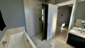 Bathtub dan shower terpisah, sandal, handuk, dan sabun