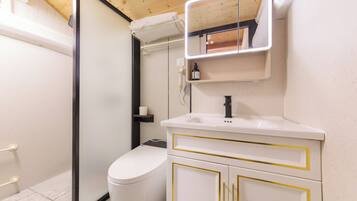 Un baño con inodoro, lavamanos con detalles dorados, espejo y toallero.