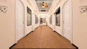 A hotel hallway with white doors numbered 101 and 105, a wooden herringbone floor, and a ceiling fan. - Le Qin Courtyard Hotel (Beijing)
