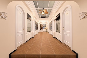 A hotel hallway with white doors numbered 101 and 105, a wooden herringbone floor, and a ceiling fan.