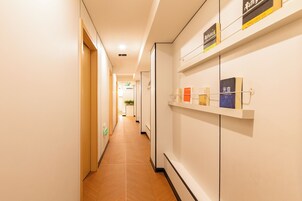 A hallway with a wooden floor, white walls, and shelves with books and signs.
