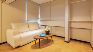 Uma sala de estar moderna com um sofá, uma mesa de centro com livros e um vaso de flores.