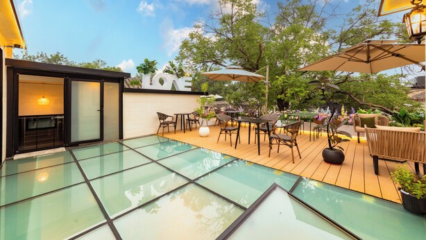 A glass-enclosed outdoor area with a pool, wooden deck, and outdoor seating. - Le Qin Courtyard Hotel (Beijing)