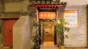 A traditional building with a red door, a signboard with Chinese characters, and two potted plants at the entrance. - Le Qin Courtyard Hotel (Beijing)