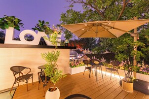 An outdoor patio with wooden flooring, a large umbrella, and a wall-mounted sign.