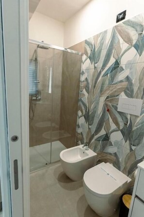 A bathroom with a shower, bidet, and toilet.