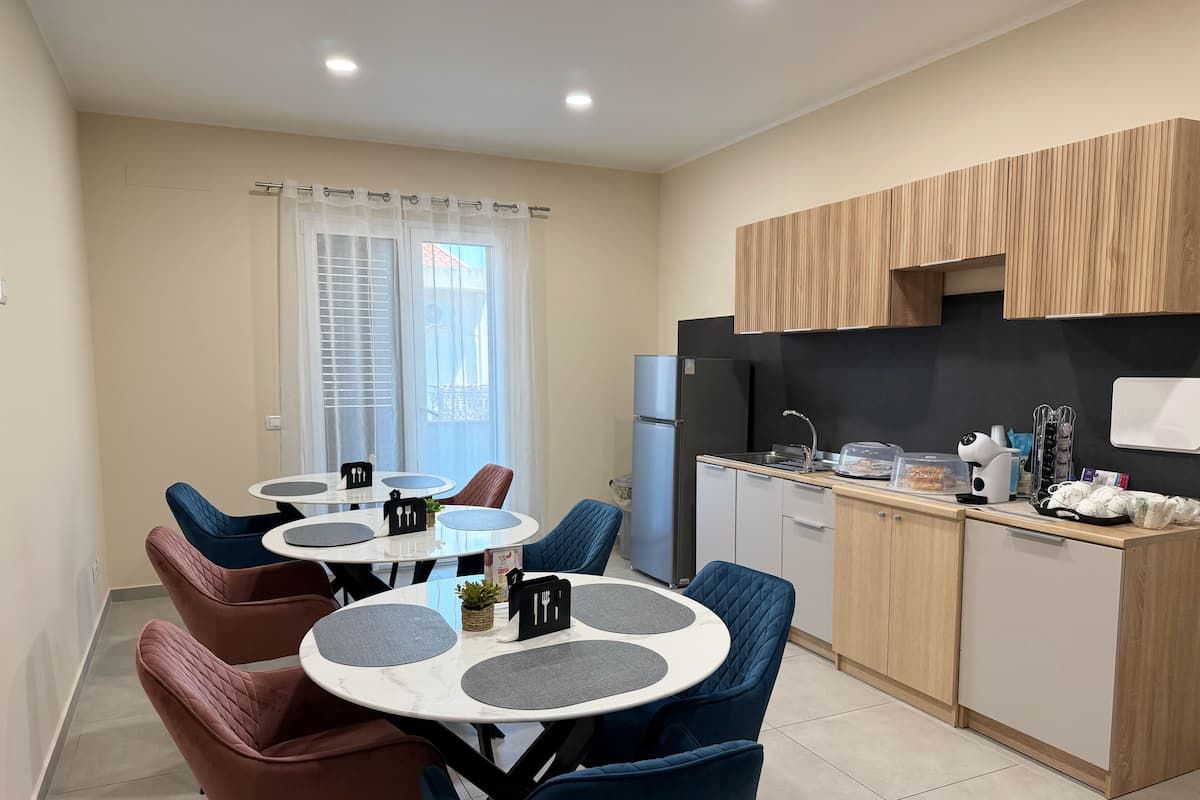 Una cocina moderna con refrigerador, estufa y armarios de madera. Hay una zona de comedor con una mesa redonda y sillas.
