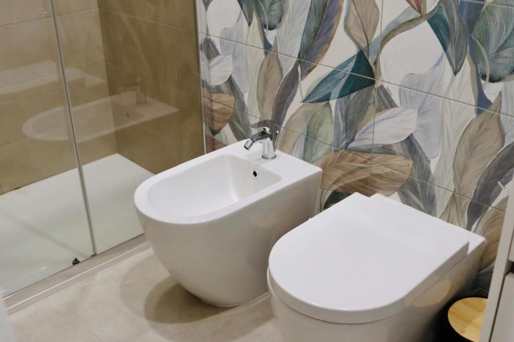 Un baño moderno con bidé, inodoro y cabina de ducha de vidrio.