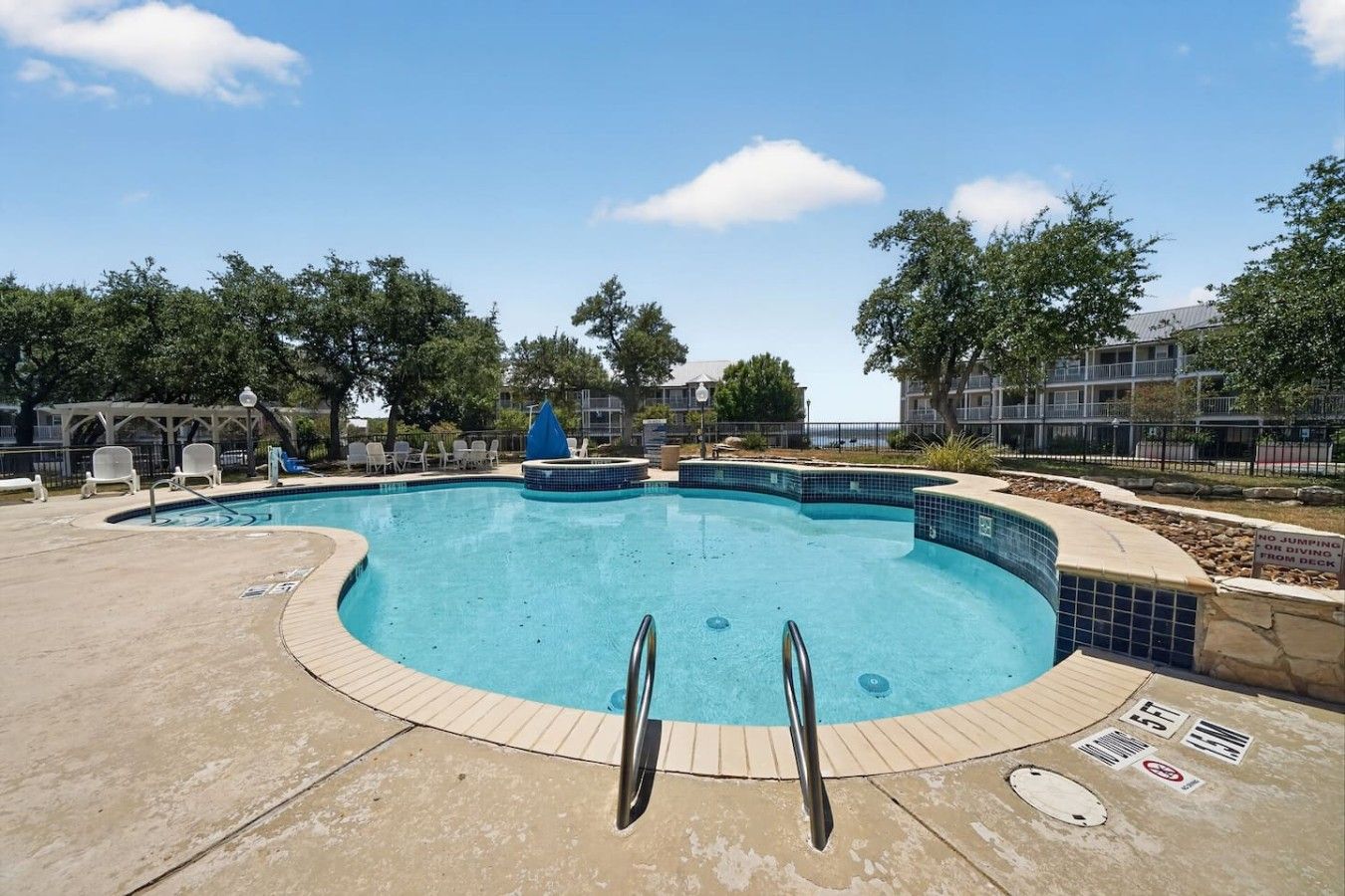 A swimming pool with a tiled edge, a lifeguard stand, and a no-jumping sign.