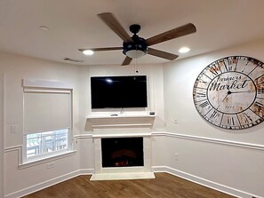 A room with a fireplace, a large wall clock, and a ceiling fan. - Relaxing 2 bd w/AC, Wi-Fi, pool Canyon Lake #424 (Canyon Lake)
