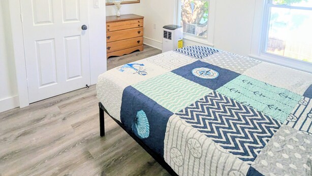 Een slaapkamer met een bed, een kaptafel, een spiegel en een raam.