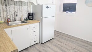 Een keuken met witte kastjes, een spoelbak, een koelkast en een koffiezetapparaat.