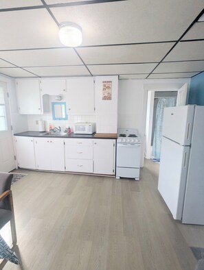 A kitchen with white cabinets, a microwave, a stove, and a refrigerator. - newly updated, pet friendly, located in a quiet neighborhood, 10 minute walk to the beach (old orchard beach)