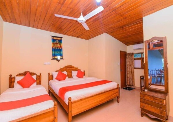 A room with two wooden beds, a ceiling fan, a mirror, and a view of the outside. - Blue Haven Hotel (Kandy)