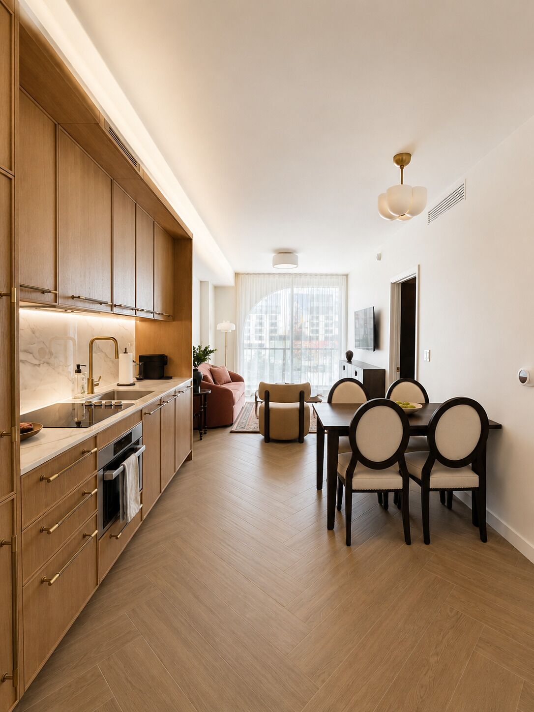 A modern kitchen with wooden cabinets, a dining area with a table and chairs, and a large window providing natural light.