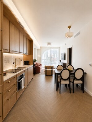 Una cocina moderna con armarios de madera, un comedor con mesa y sillas, y un ventanal que proporciona luz natural.