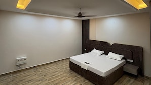 Quarto moderno com cama, mesa de cabeceira, ventoinha de teto e iluminação embutida.