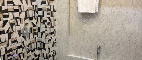 A bathroom with a geometric tile wall, a shower, a toilet, and a sink.
