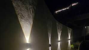 Un corridoio con illuminazione moderna a parete e motivi circolari sul pavimento.