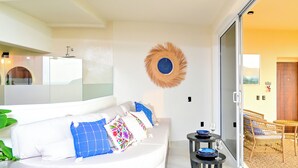 Un soggiorno moderno con un divano bianco, un elemento decorativo a parete rotondo e un'area pranzo con mobili in vimini.