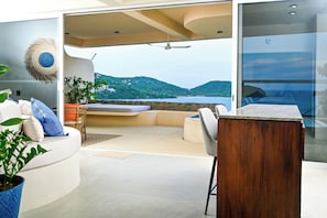 Un intérieur moderne avec un canapé aux lignes courbes, une table en bois et une vue sur la mer.