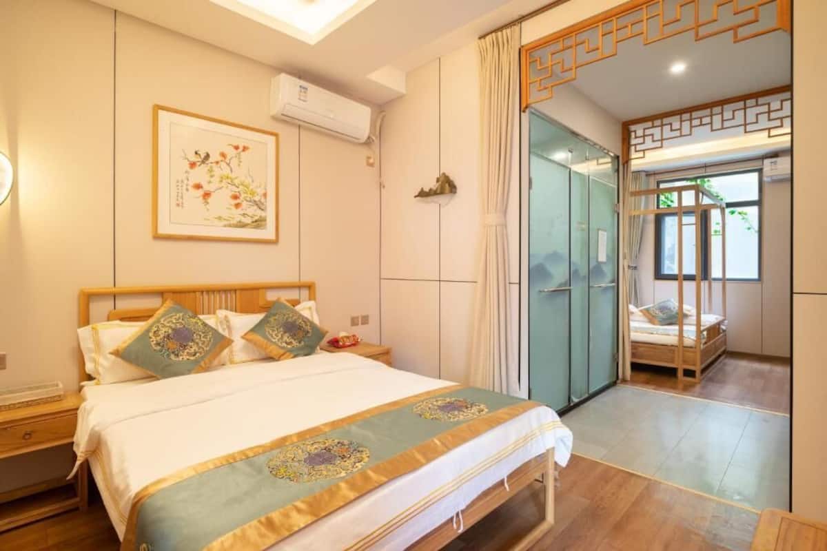 Habitación de hotel con cama, mesita de noche, aire acondicionado de pared y una obra de arte enmarcada.
