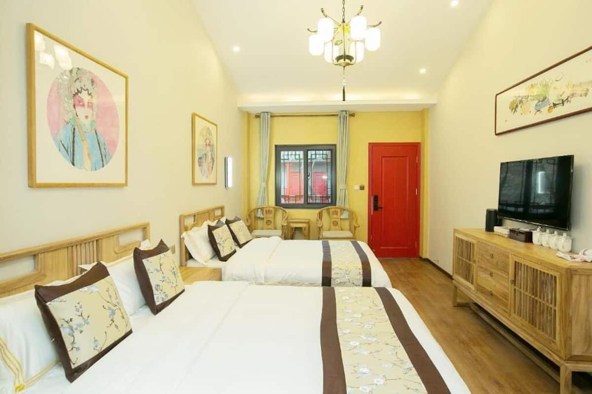 Una habitación de hotel con dos camas, un televisor, un armario de madera y obras de arte en las paredes.